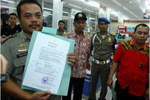 Petugas satpol PP menunjukan surat perintah penyegelan mini market.